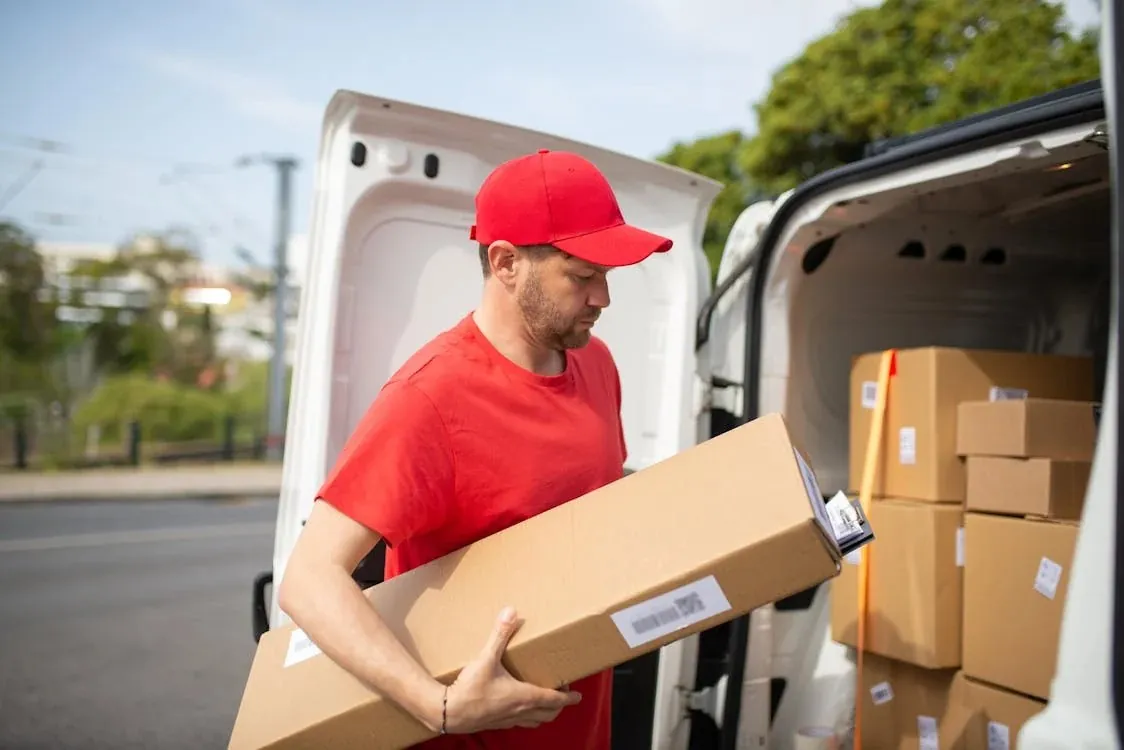Mover carrying a box out of a white van loaded with boxes