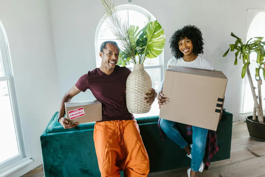 Smiling couple holding boxes in their new home