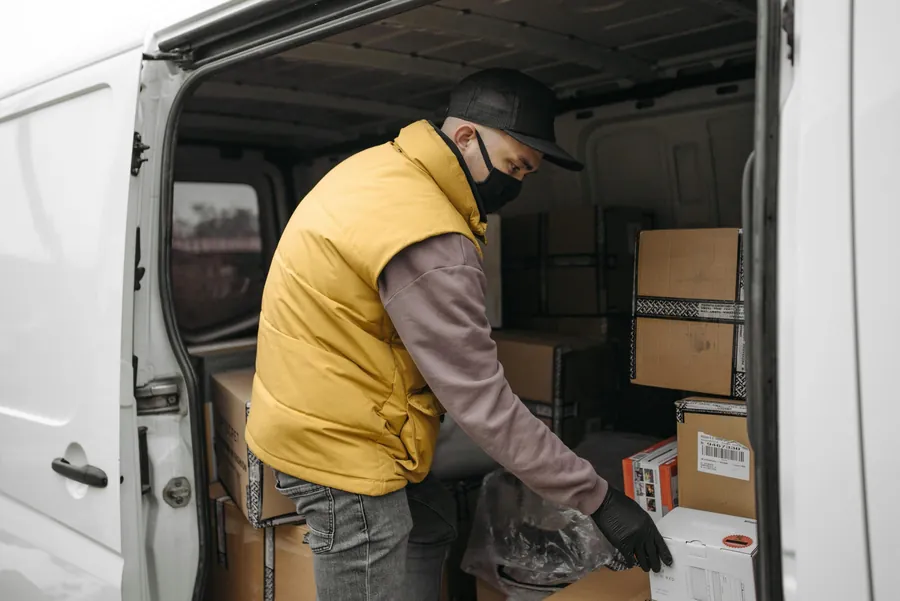 Worker loading boxes into the back of a white van